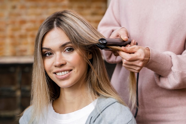 Mulher sorridente a arrumar o cabelo em casa