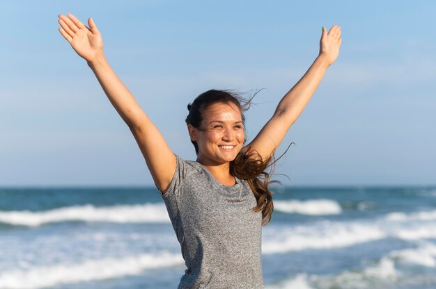 Mulher sorridente a fazer exercício na praia