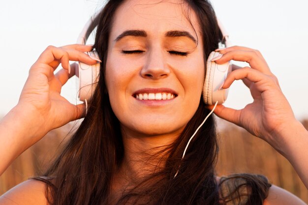 Mulher sorridente a ouvir música ao ar livre ao sol