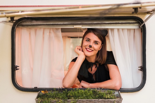 Mulher sorridente a posar na janela da caravana