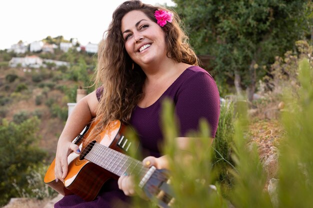 Mulher sorridente ao ar livre com guitarra