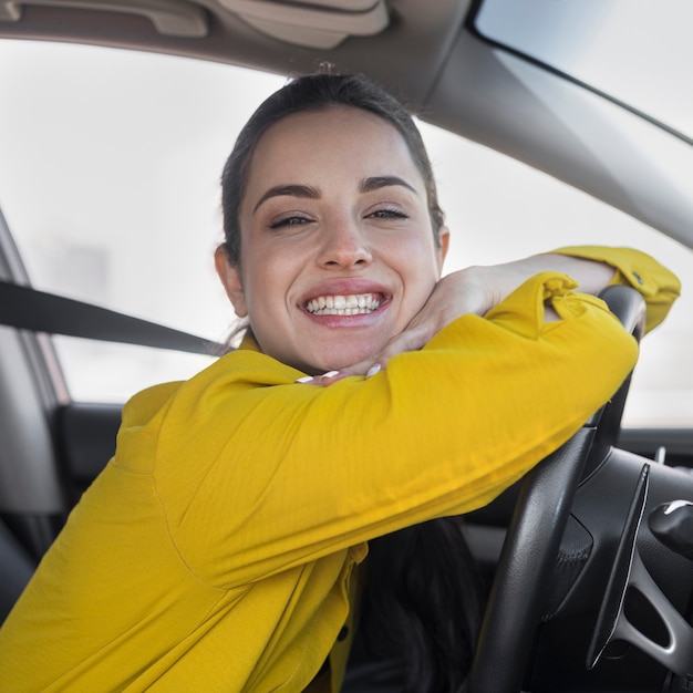 Foto grátis mulher sorridente, apoiando-se no volante