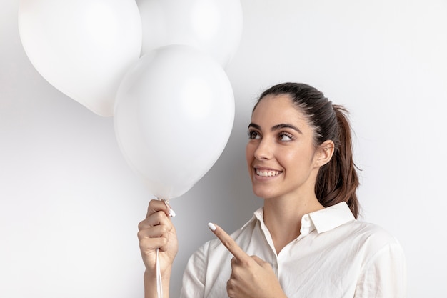 Foto grátis mulher sorridente apontando balões à mão