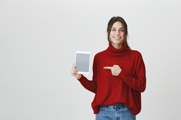 Mulher sorridente, apontando para a tela do tablet digital