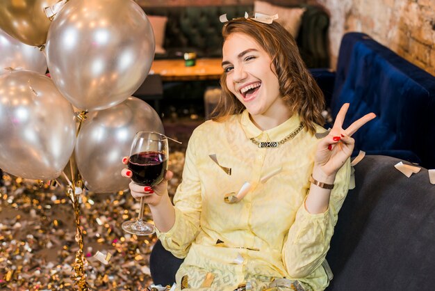 Mulher sorridente atraente desfrutando de festa segurando o copo de vinho