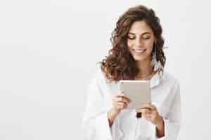 Foto grátis mulher sorridente atraente olhando para um tablet digital