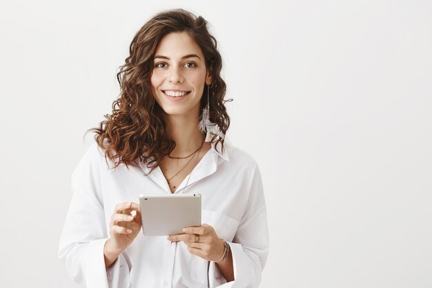 Mulher sorridente atraente usando tablet digital