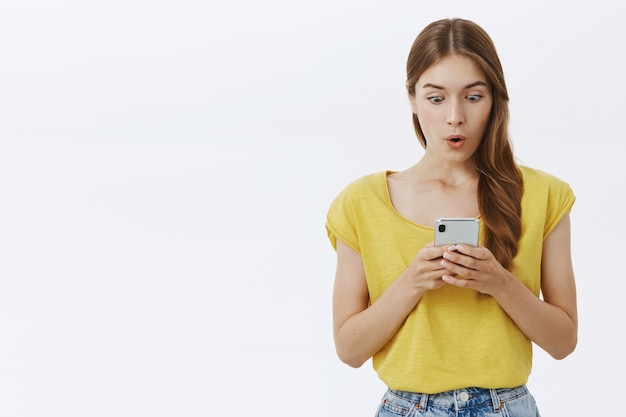 Mulher sorridente atraente usando telefone celular, mensagem de texto no aplicativo ou rede social