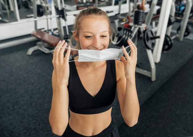 Mulher sorridente colocando sua máscara médica na academia