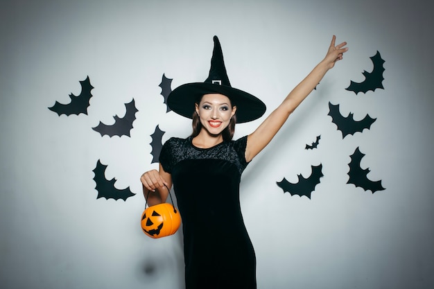 Mulher sorridente com abóbora e chapéu de halloween