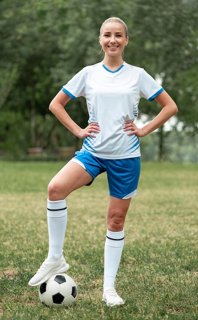 Mulher sorridente com bola de futebol