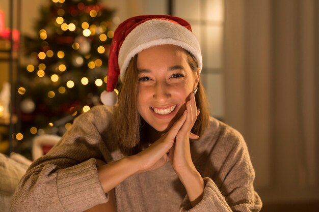 Mulher sorridente com chapéu de Papai Noel posando