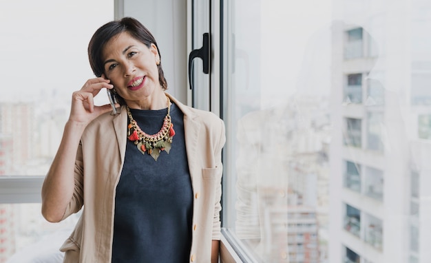 Mulher sorridente com colar falando ao telefone