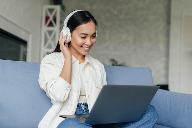 Mulher sorridente com fones de ouvido trabalhando em um laptop
