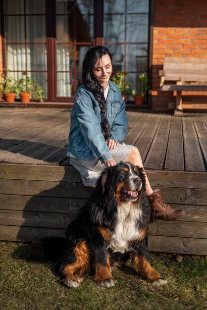 Mulher sorridente com foto completa acariciando cachorro