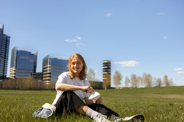 Foto grátis mulher sorridente com foto completa sentada na grama