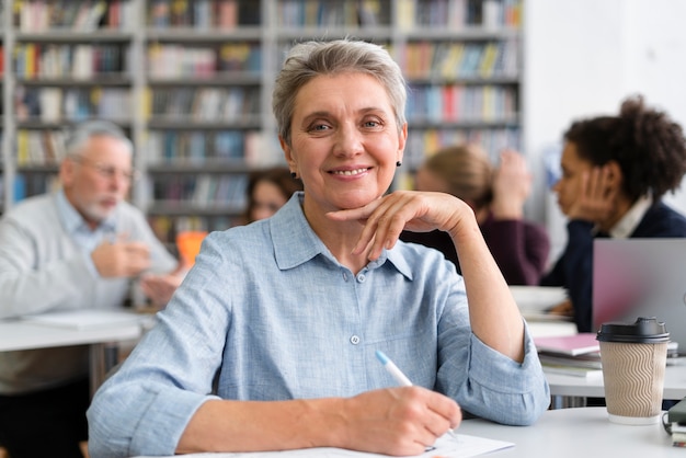 Mulher sorridente com foto média na biblioteca