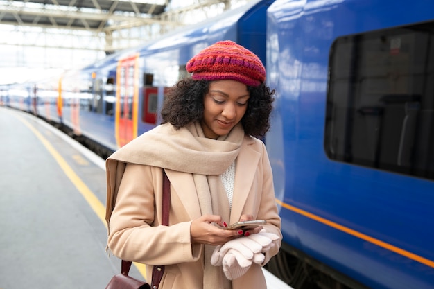 Foto grátis mulher sorridente com foto média na estação de trem