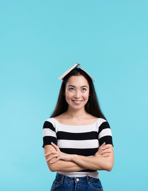 Mulher sorridente com livro na cabeça