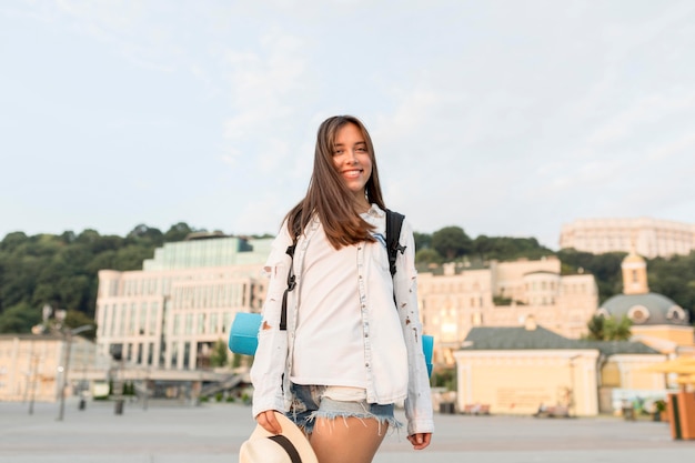 Mulher sorridente com mochila e chapéu posando durante a viagem