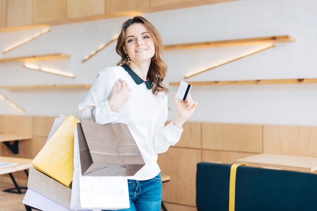 Mulher sorridente com sacos de papel e cartão de crédito