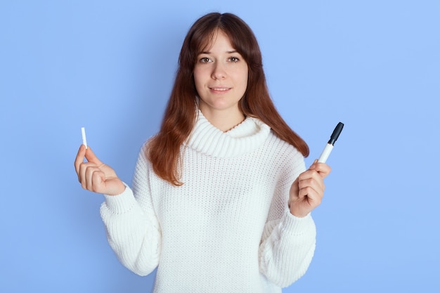 Foto grátis mulher sorridente com suéter branco de pé sobre o azul