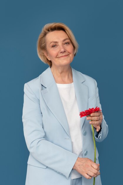 Mulher sorridente com tiro médio segurando uma flor