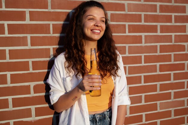 Foto grátis mulher sorridente com tiro médio segurando uma garrafa