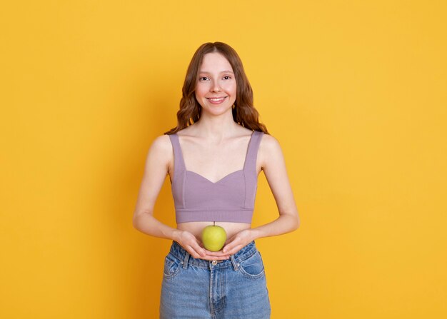 Mulher sorridente com tiro médio segurando uma maçã