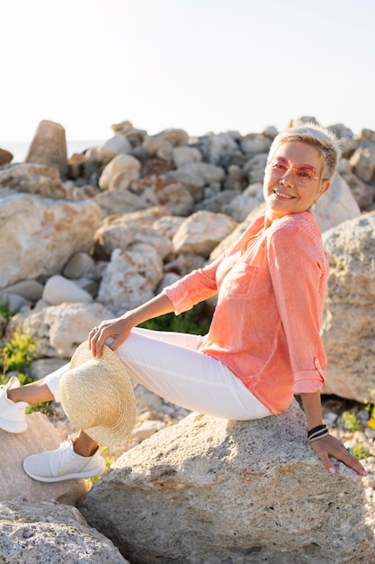 Mulher sorridente com vista lateral posando sobre pedras