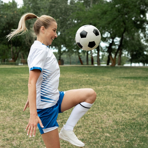 Mulher sorridente com vista lateral treinando com bola