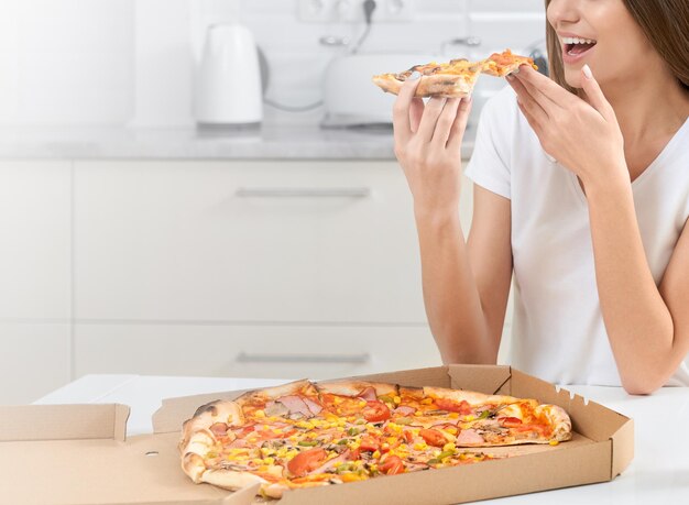 Mulher sorridente comendo pizza de pedaço