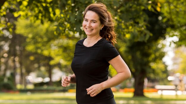 Mulher sorridente correndo em roupas esportivas