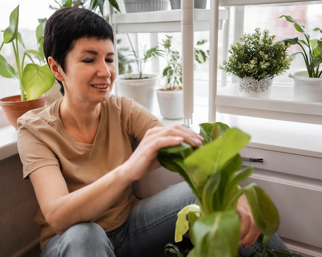 Mulher sorridente cuidando de plantas de interior