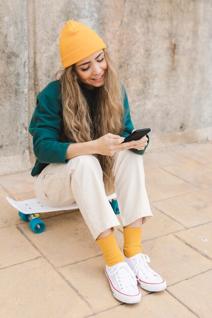 Mulher sorridente de alto ângulo sentado no skate