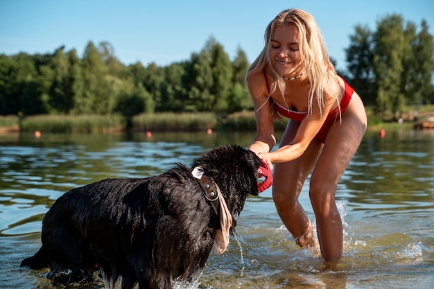 Mulher sorridente de tiro completo brincando com cachorro