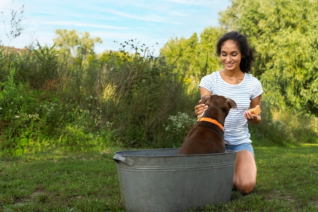 Foto grátis mulher sorridente de tiro completo lavando cachorro