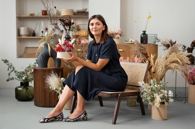 Foto grátis mulher sorridente de tiro completo segurando flores