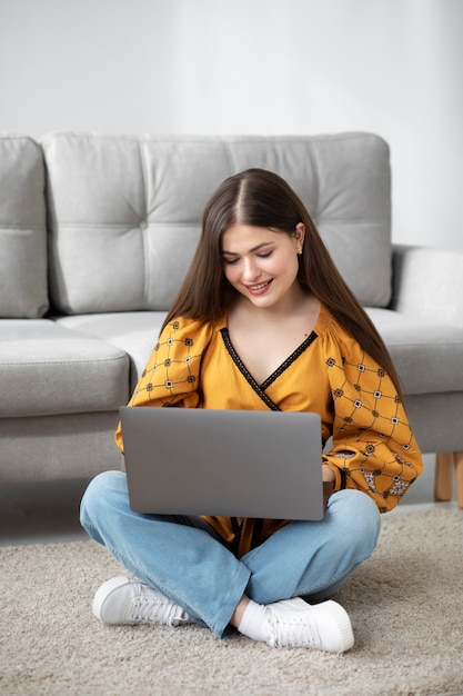 Mulher sorridente de tiro completo segurando laptop