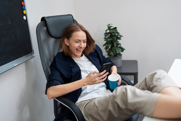 Mulher sorridente de tiro completo segurando o telefone no trabalho