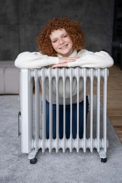 Mulher sorridente de tiro completo sentada com aquecedor