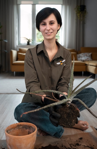 Mulher sorridente de tiro completo transplantando plantas em casa