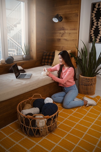 Foto grátis mulher sorridente de tiro completo tricotando em casa