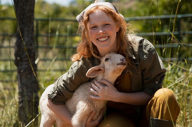 Foto grátis mulher sorridente de tiro médio abraçando um cordeiro