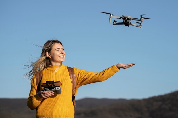 Mulher sorridente de tiro médio com drone do lado de fora
