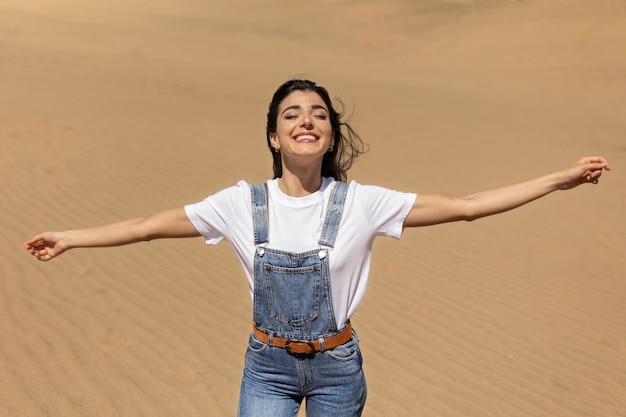 Mulher sorridente de tiro médio no deserto
