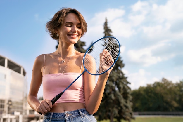 Foto grátis mulher sorridente de tiro médio segurando a raquete