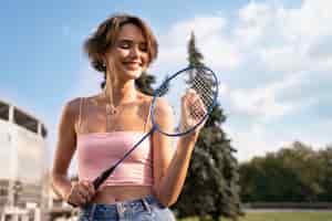 Foto grátis mulher sorridente de tiro médio segurando a raquete