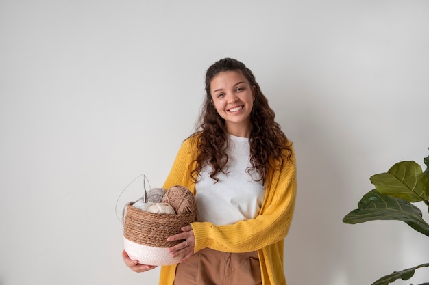 Mulher sorridente de tiro médio segurando cesta com fios