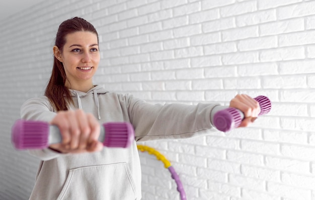 Foto grátis mulher sorridente de tiro médio segurando halteres